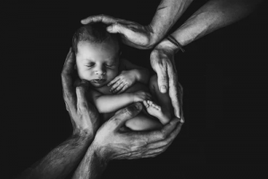 Baby held in four hands 